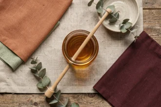 Palette de couleurs associées au miel avec swatches en terre cuite, vert sauge et bordeaux posés sur lin naturel