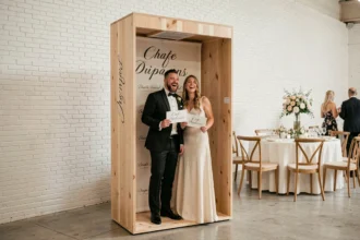Photobooth en bois de taille standard installé dans une salle de mariage avec deux invités posant à l'intérieur